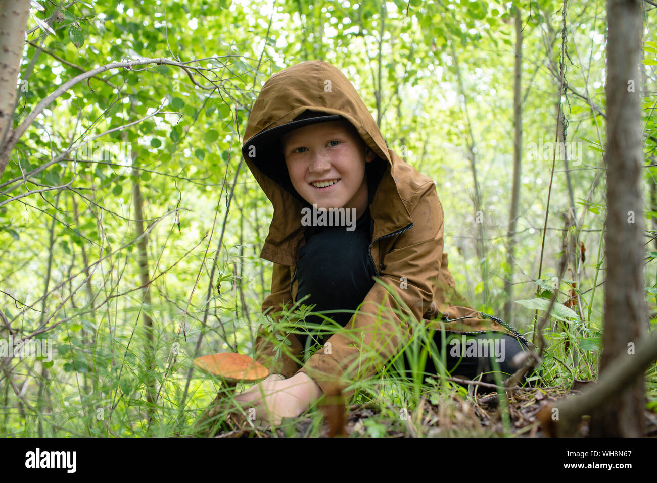 Portrait of smiling boy la collecte de champignons dans les bois Banque D'Images