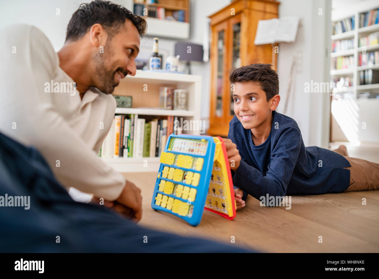 Père et fils se trouvant sur le plancher à la lecture d'un jeu Banque D'Images Père et fils se trouvant sur le plancher à la lecture d'un jeu Banque D'Images