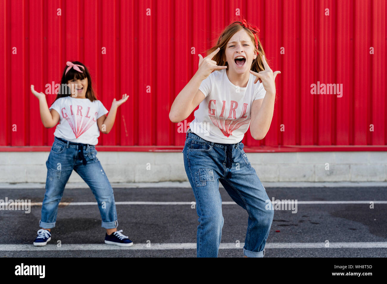 Sœurs rocking en face de red wall Banque D'Images