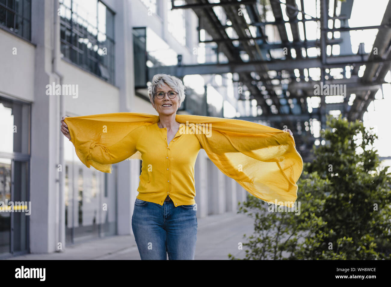 Portrait of smiling mature woman wearing cardigan jaune et foulard Banque D'Images