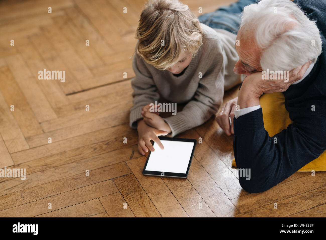 Grand-père et petit-fils gisant sur le sol à l'aide d'un comprimé Banque D'Images