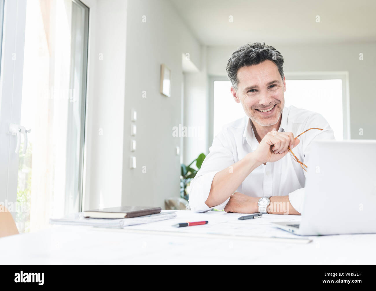 Assis dans le bureau de l'architecte lumineux, using laptop Banque D'Images