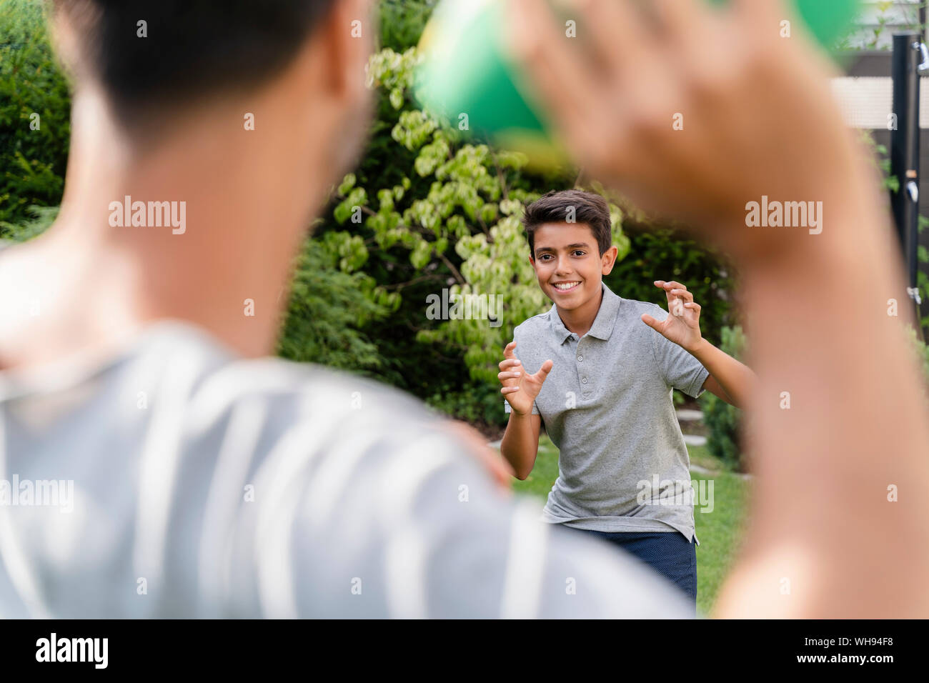 Père et fils jouant avec american football in garden Banque D'Images