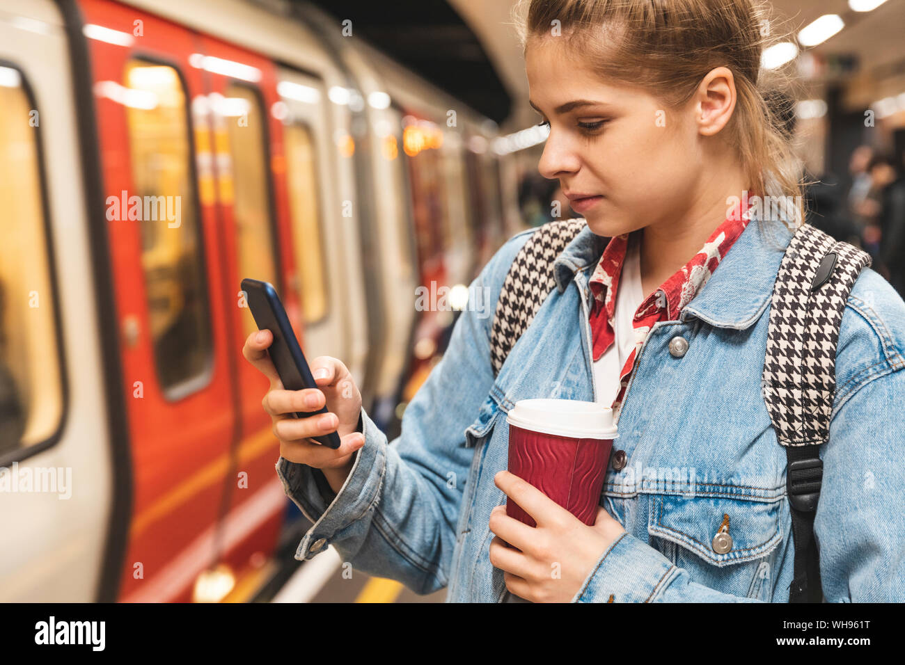 Jeune femme au métro station en utilisant un smartphone Banque D'Images