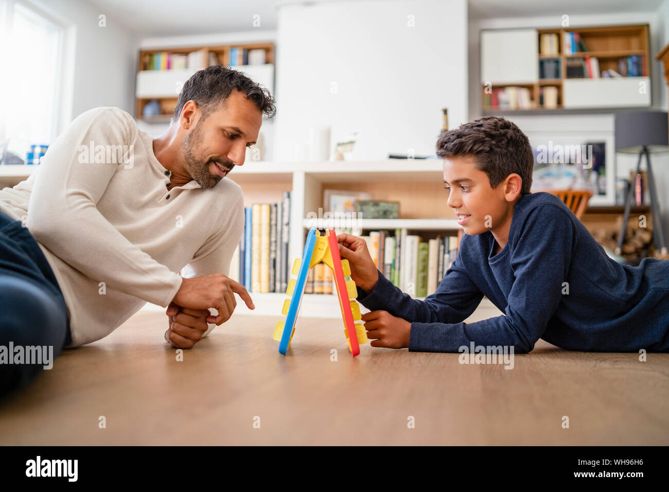 Père et fils se trouvant sur le plancher à la lecture d'un jeu Banque D'Images Père et fils se trouvant sur le plancher à la lecture d'un jeu Banque D'Images