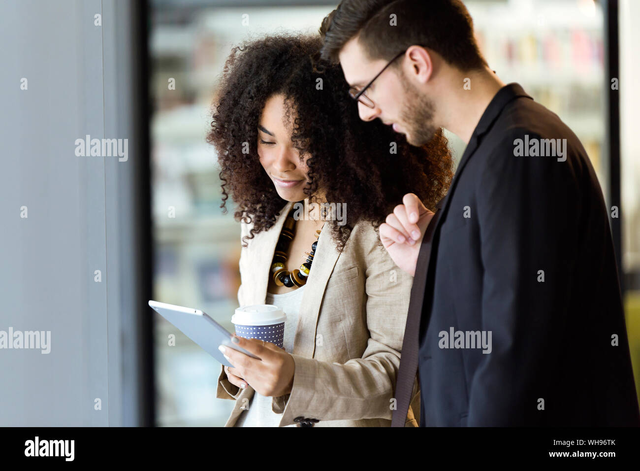 Deux jeunes partenaires d'affaires à l'aide d'une tablette dans un couloir Banque D'Images