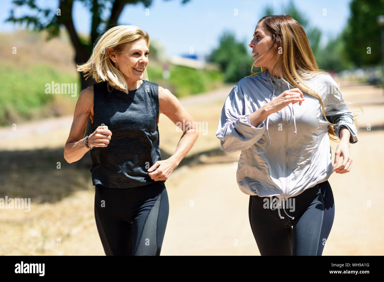 Young woman running avec sa fille dans un parc Banque D'Images