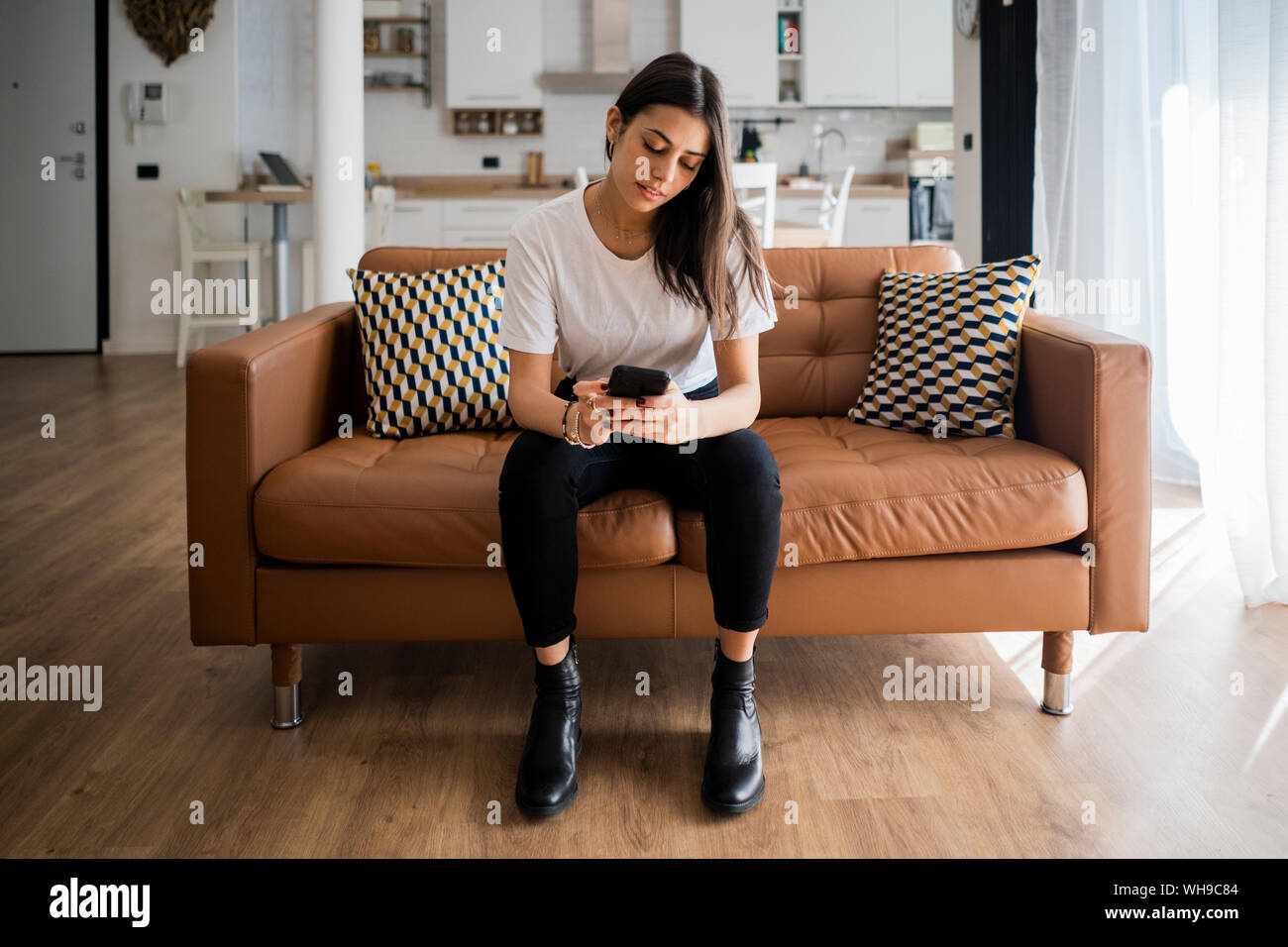 Jeune femme sur la table à la maison using cell phone Banque D'Images