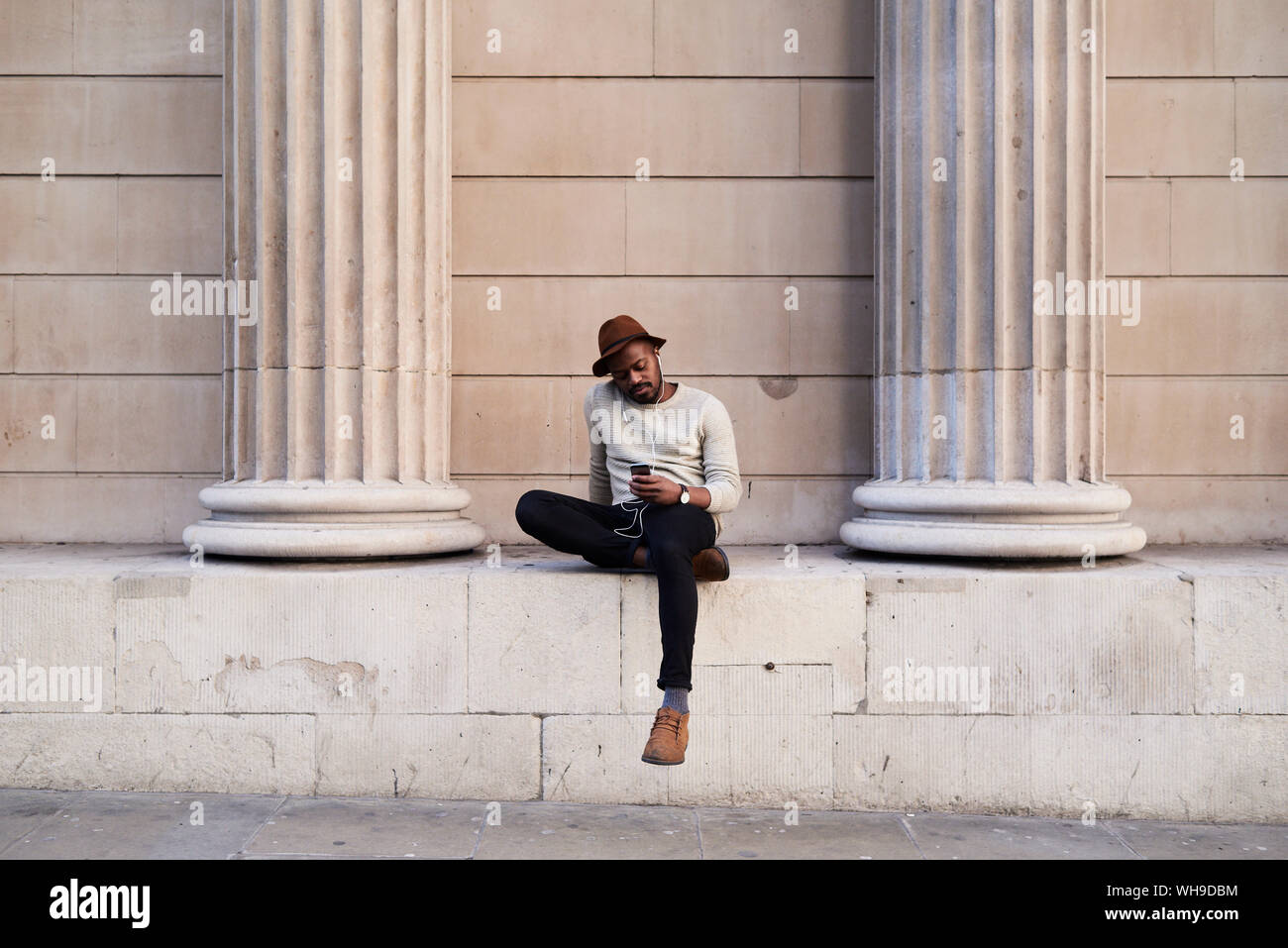 Mid adult wearing hat listening music Banque D'Images