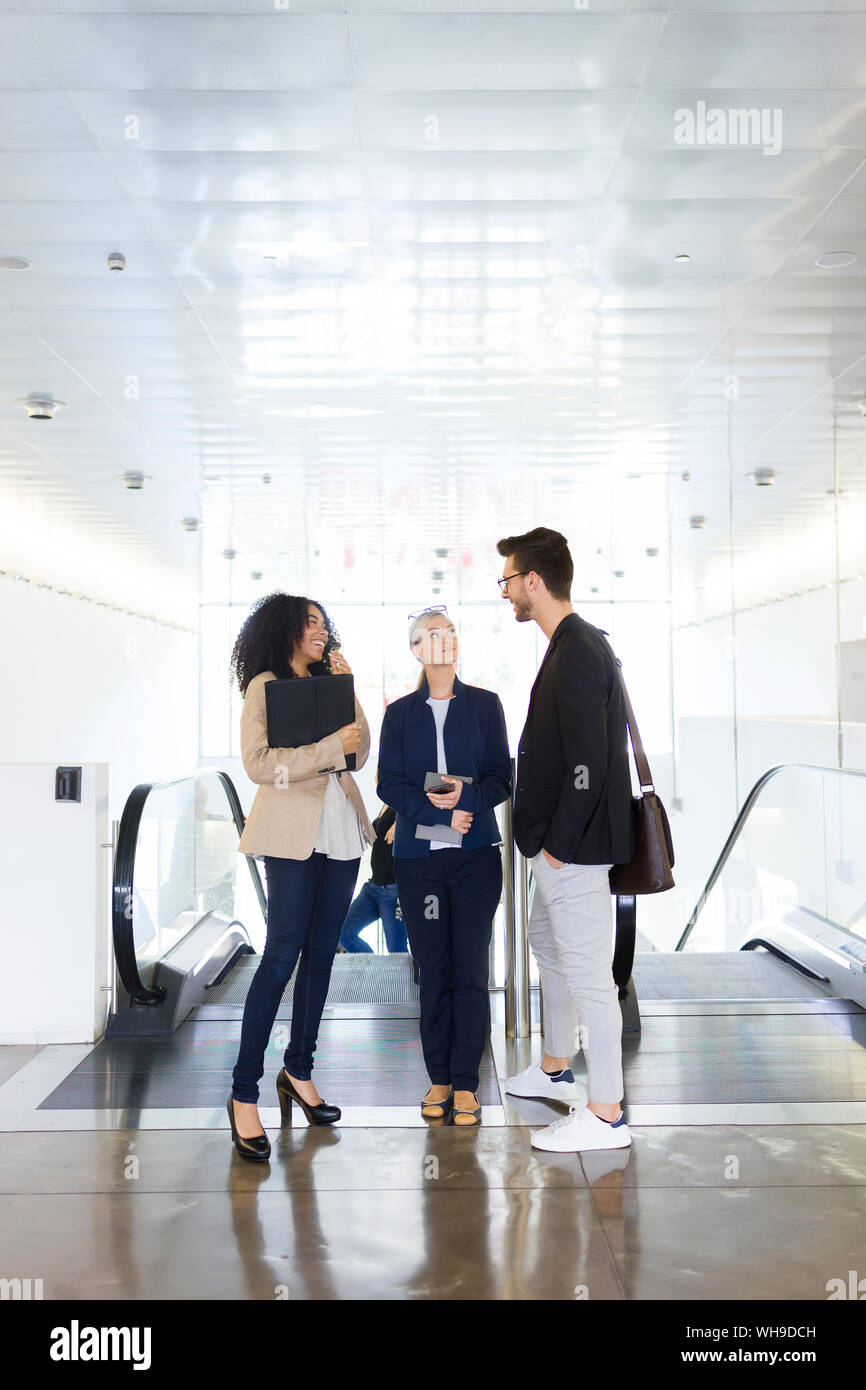 Les jeunes gens d'affaires de parler à un escalator Banque D'Images