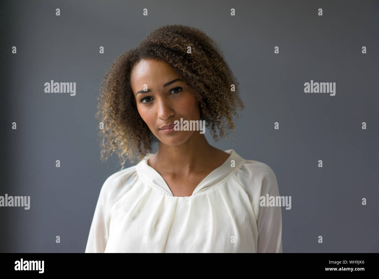 Portrait of young woman wearing blouse blanche contre l'arrière-plan gris Banque D'Images