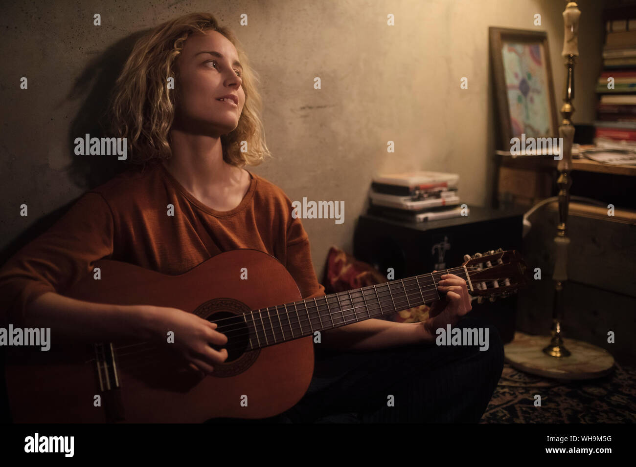 Jeune femme jouant de la guitare à la maison Banque D'Images