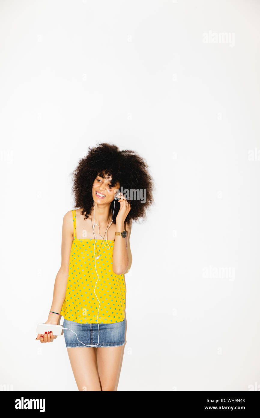 Jeune femme en utilisant son téléphone portable pour écouter de la musique, fond blanc Banque D'Images