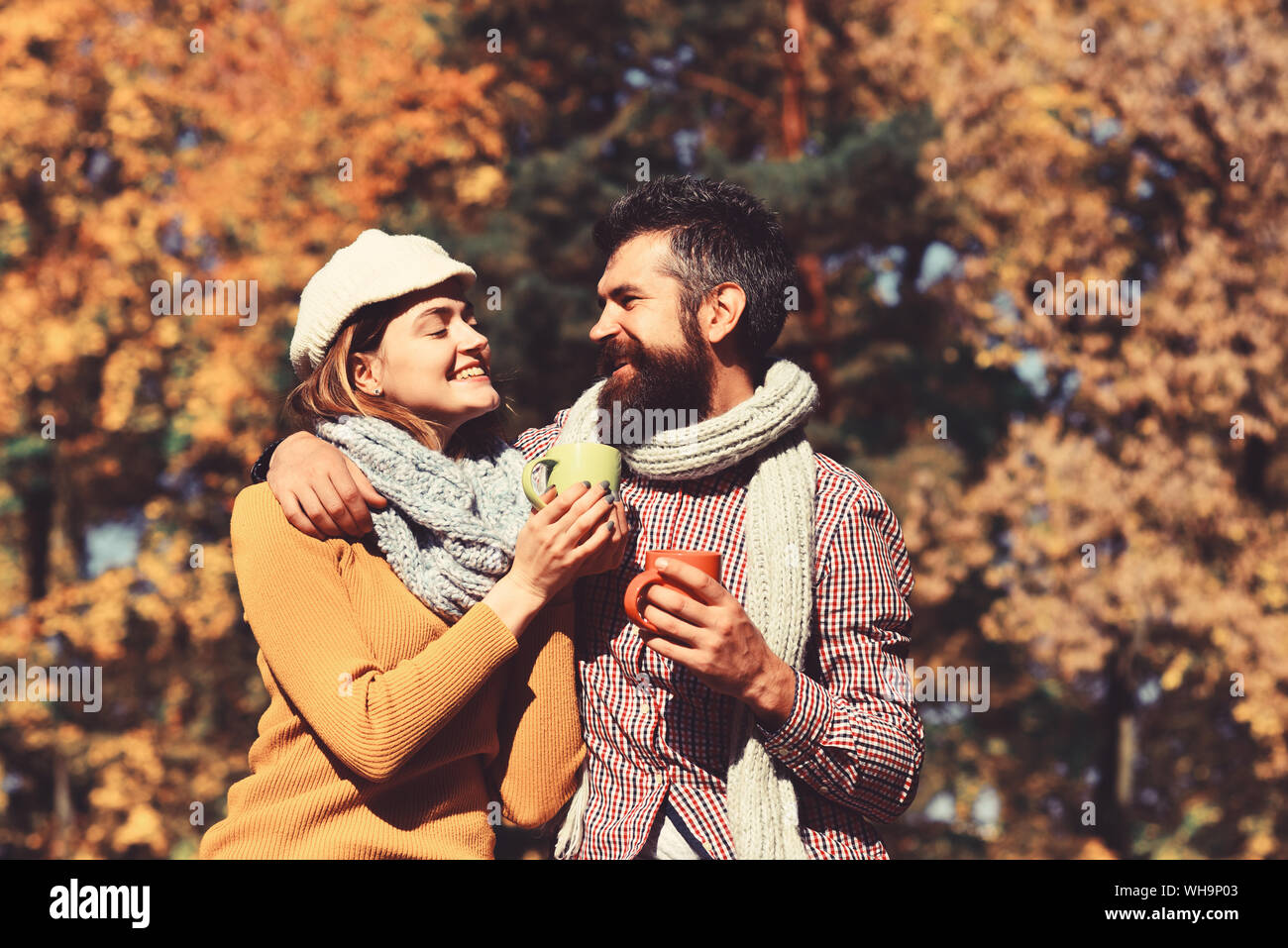 La famille et l'automne chaud verre concept. Couple amoureux de foulards se  trouve dans la région de park holding tasses de thé ou de café. L'homme et  de la femme avec des