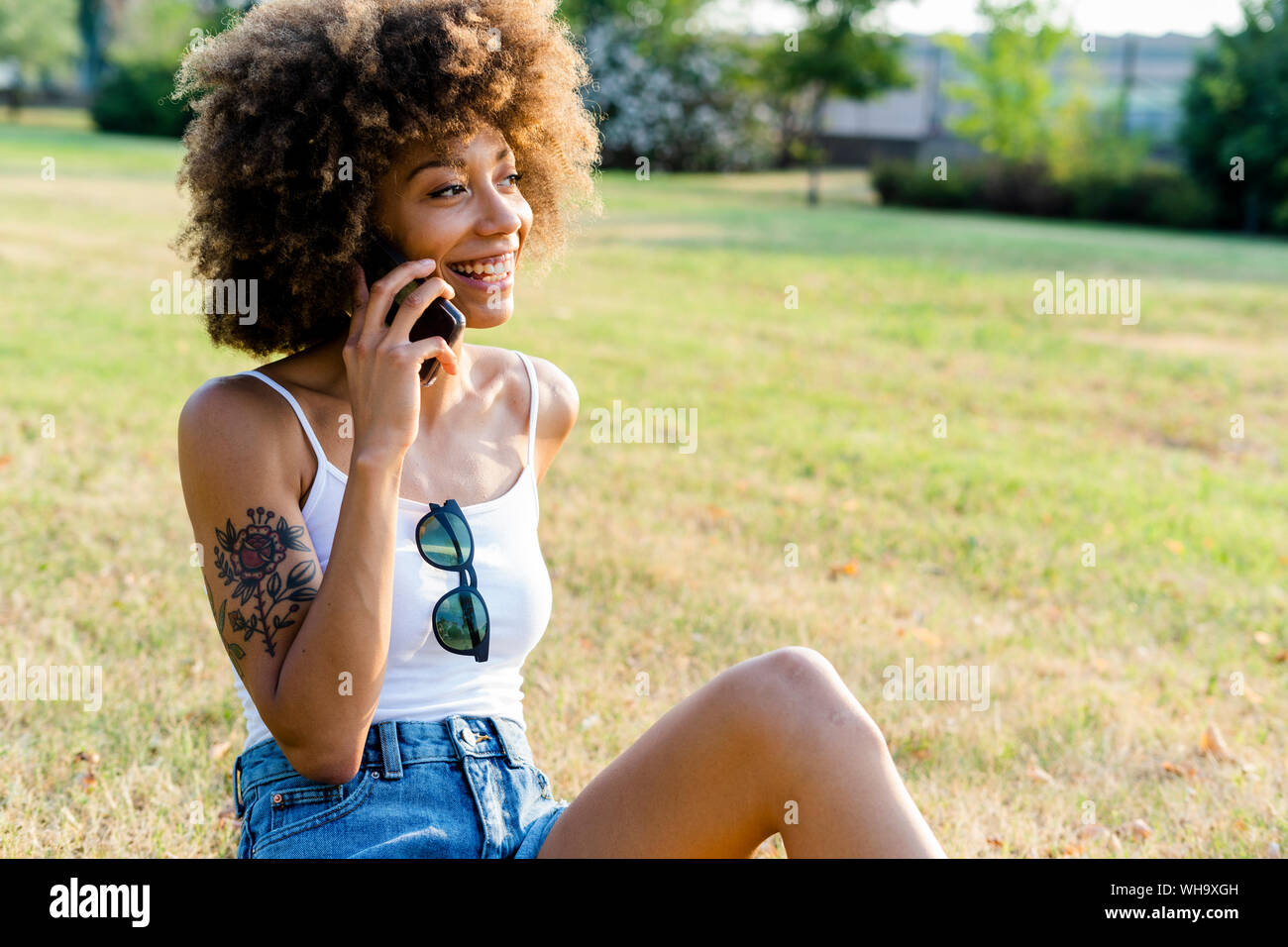 Portrait of happy young woman on the phone assis sur un pré Banque D'Images
