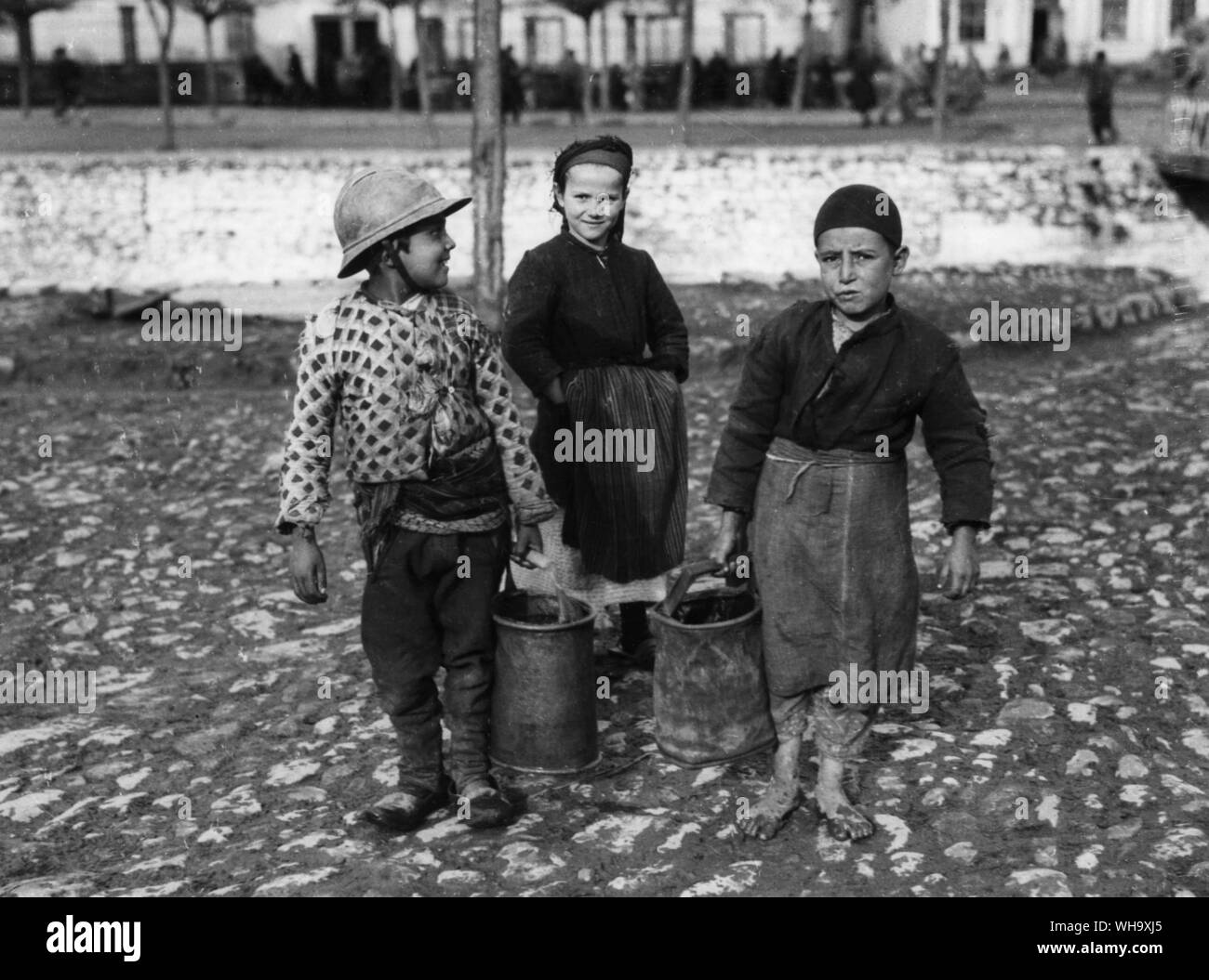 WW1 : Capture de Monastir. Les enfants vont chercher de l'eau pour les soldats. L'un porte un casque français. Novembre 1916. Banque D'Images