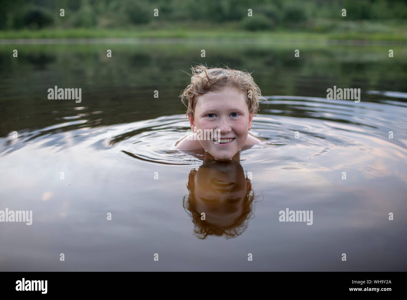 Portrait of smiling boy swimming in a lake Banque D'Images