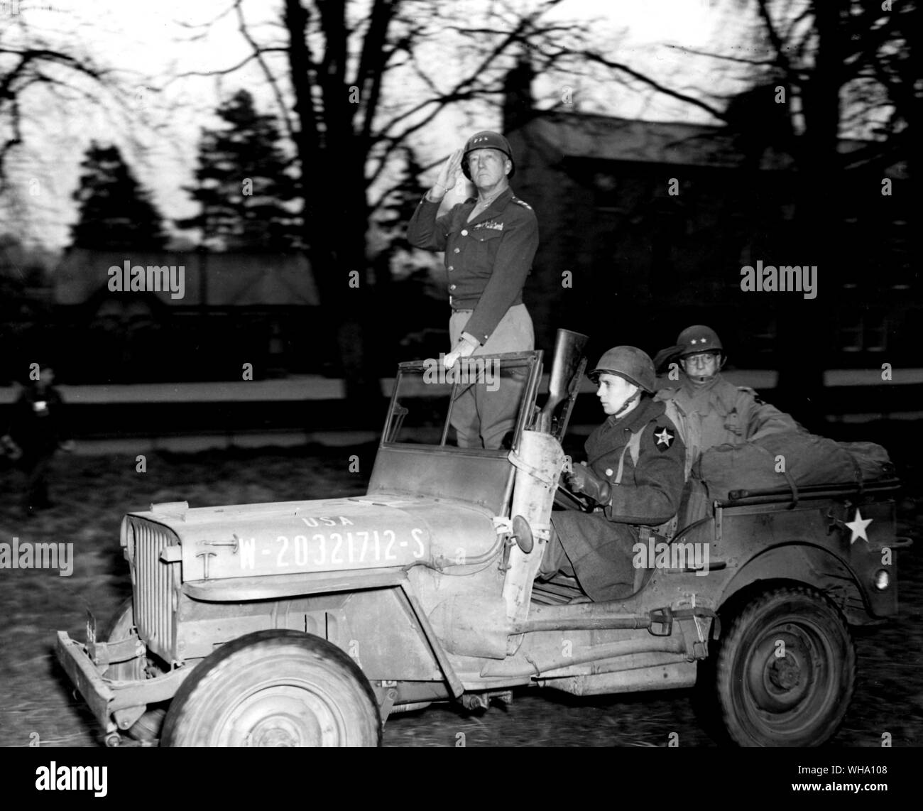 WW2 : Lt Gen George S Patton Jr. Troisième armée, debout dans une jeep, salue les troupes de la 2 Division, sous son commandement, comme ils passent dans l'étude au cours d'une tournée d'inspection, dans Armargh, dans le Nord de l'Angleterre. Assis à l'arrière de la jeep est le Major-général Walter E Robertson, CG, 2e Division. 3e avril 1944. Banque D'Images