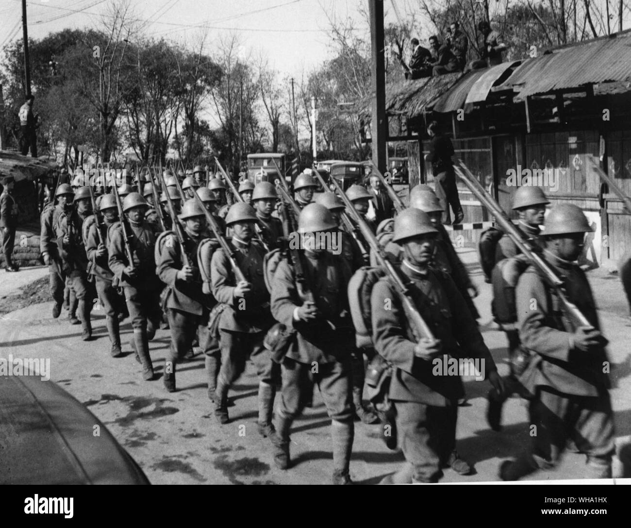 WW2 : la victoire bombardé Mars à Shanghai. Les troupes japonaises marchant au-delà d'un poste dans la région de Jessfield. Les soldats japonais ont été attaqué par un chinois qui ont lancé une grenade au milieu d'eux mais les Chinois a été tué. Banque D'Images