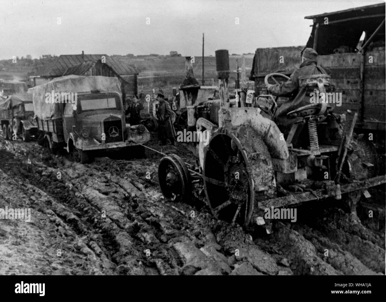 WW2 : la boue sur le front de l'Est. Terrain marécageux de la Russie durant la saison des pluies d'automne. Les camions de l'armée allemande coincé sur une route boueuse sur le front de l'Est, ont à être tiré par un tracteur de transport. Banque D'Images