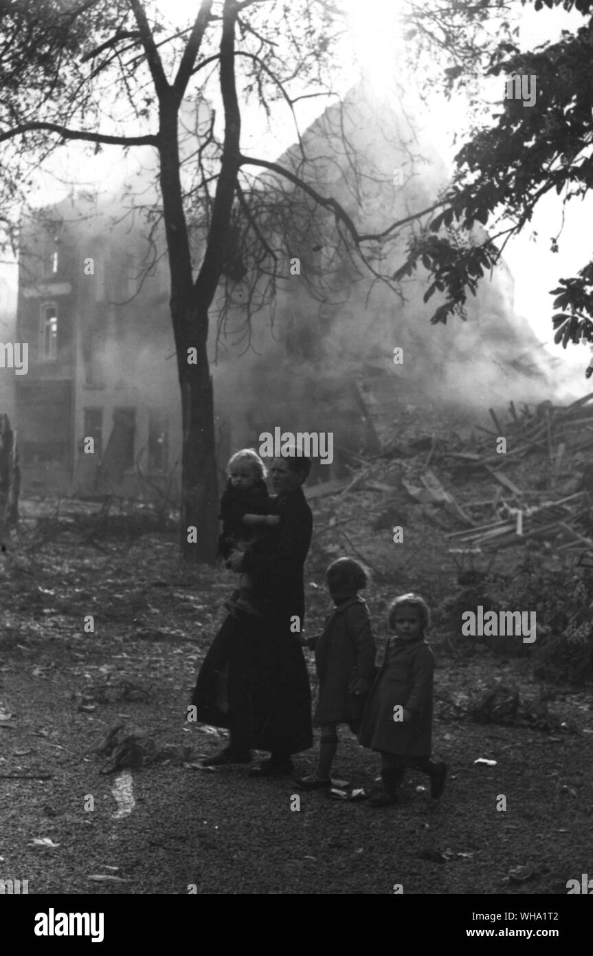 WW2 : la mère et l'enfant wlkaing cours des ruines fumantes d'Enghein. Banque D'Images