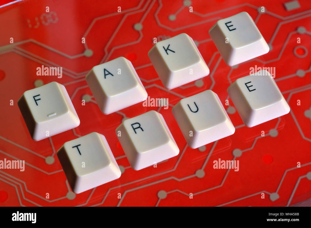 Touches du clavier forment le mot FAUX VRAI sur circuit électrique rouge en arrière-plan. Banque D'Images