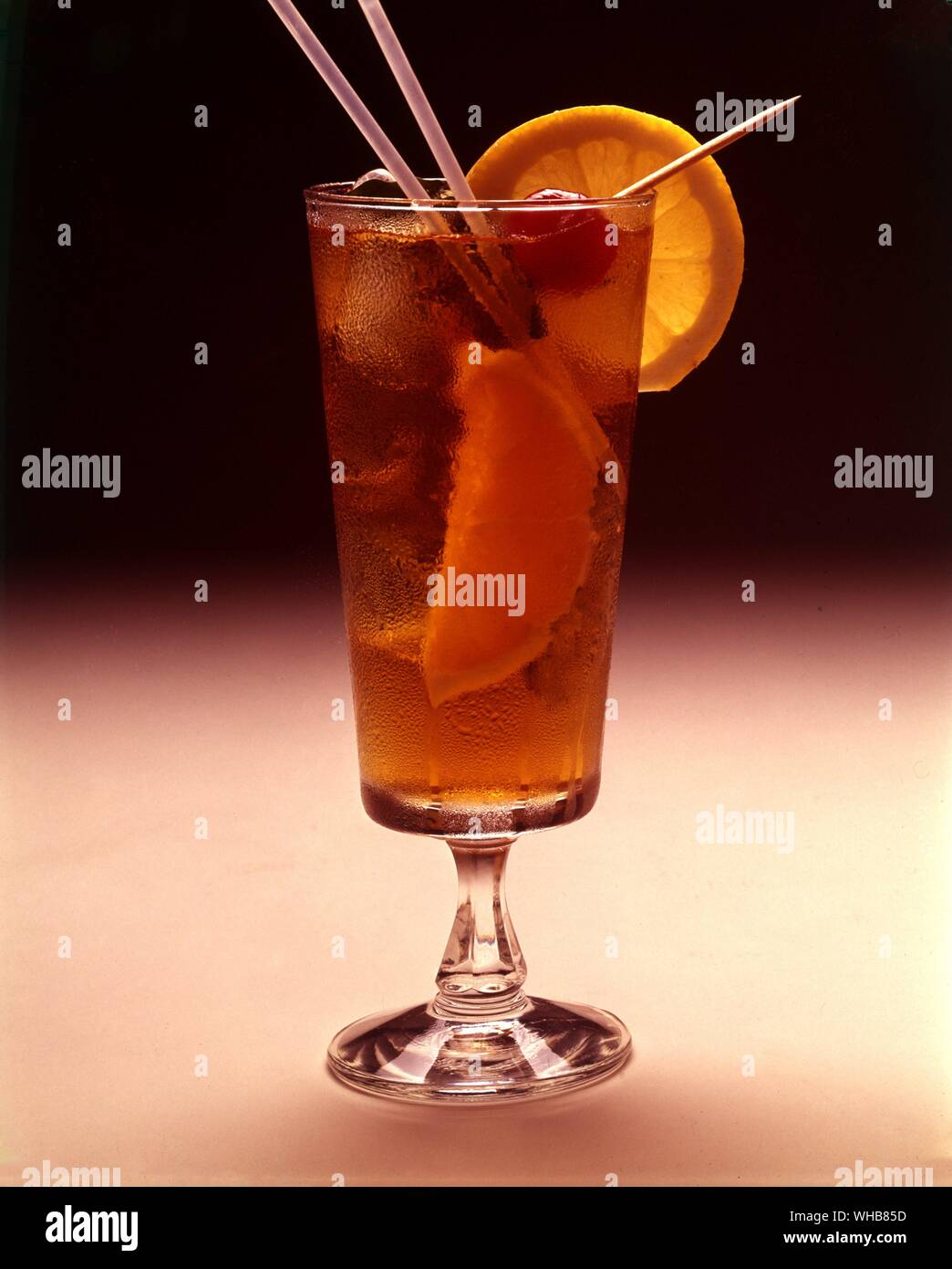 Verre avec paille et garnir de tranches de citron et cerise sur un bâton. Banque D'Images