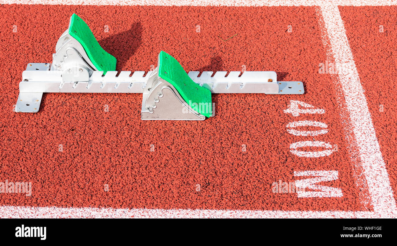 Un ensemble de l'athlétisme sprinters blocs de départ sont mis en place à la ligne de départ de 400 mètres sur une piste rouge. Banque D'Images