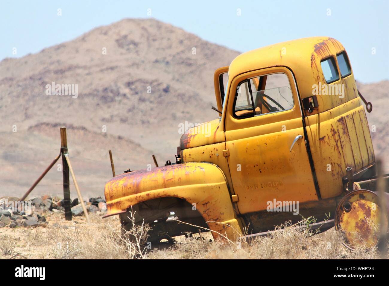 Gros plan d'un ancien chariot jaune cassé dans un champ herbacé sec avec un arrière-plan flou Banque D'Images