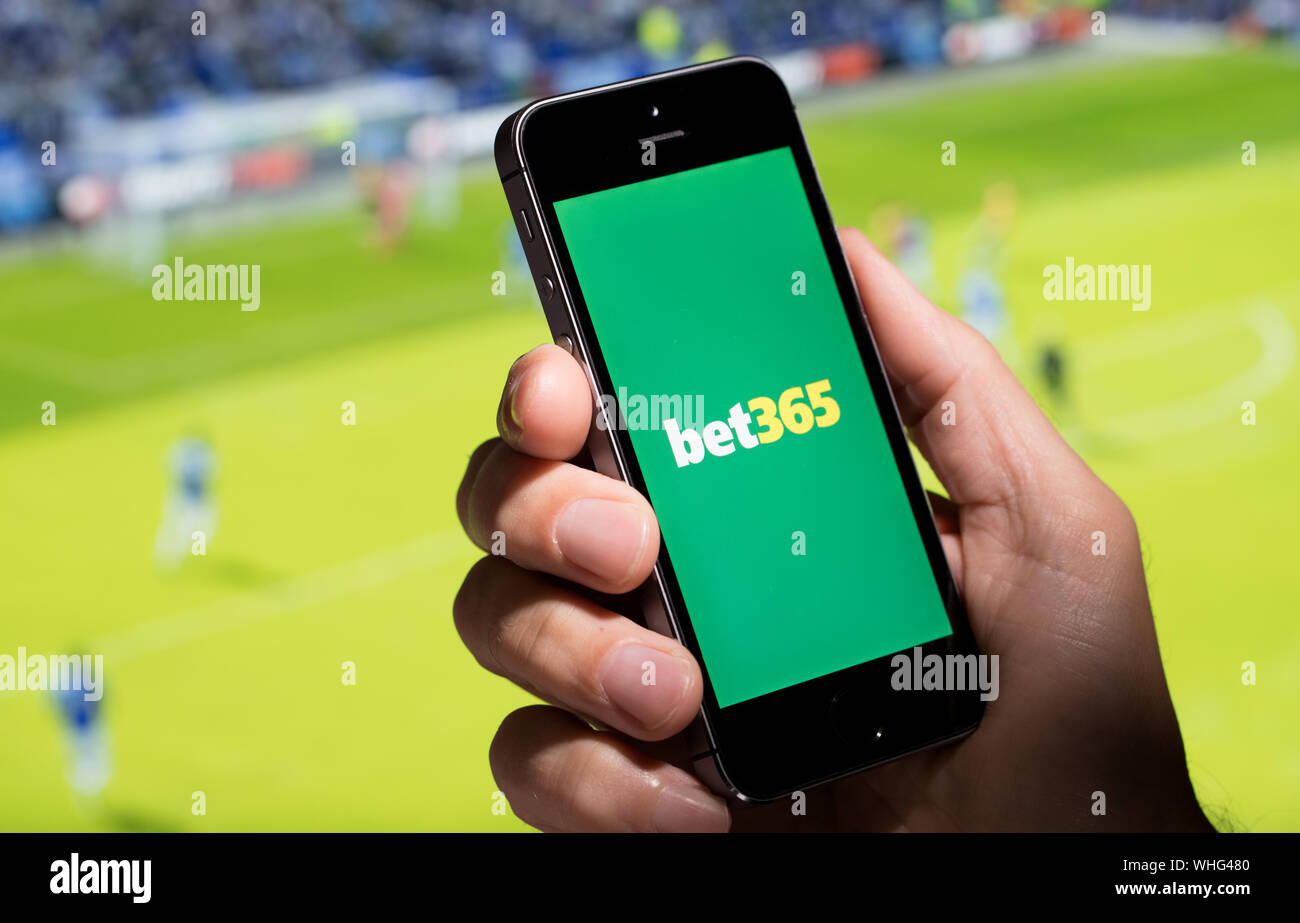 Un homme à la recherche au site web app Bet365 tout en regardant le foot Banque D'Images