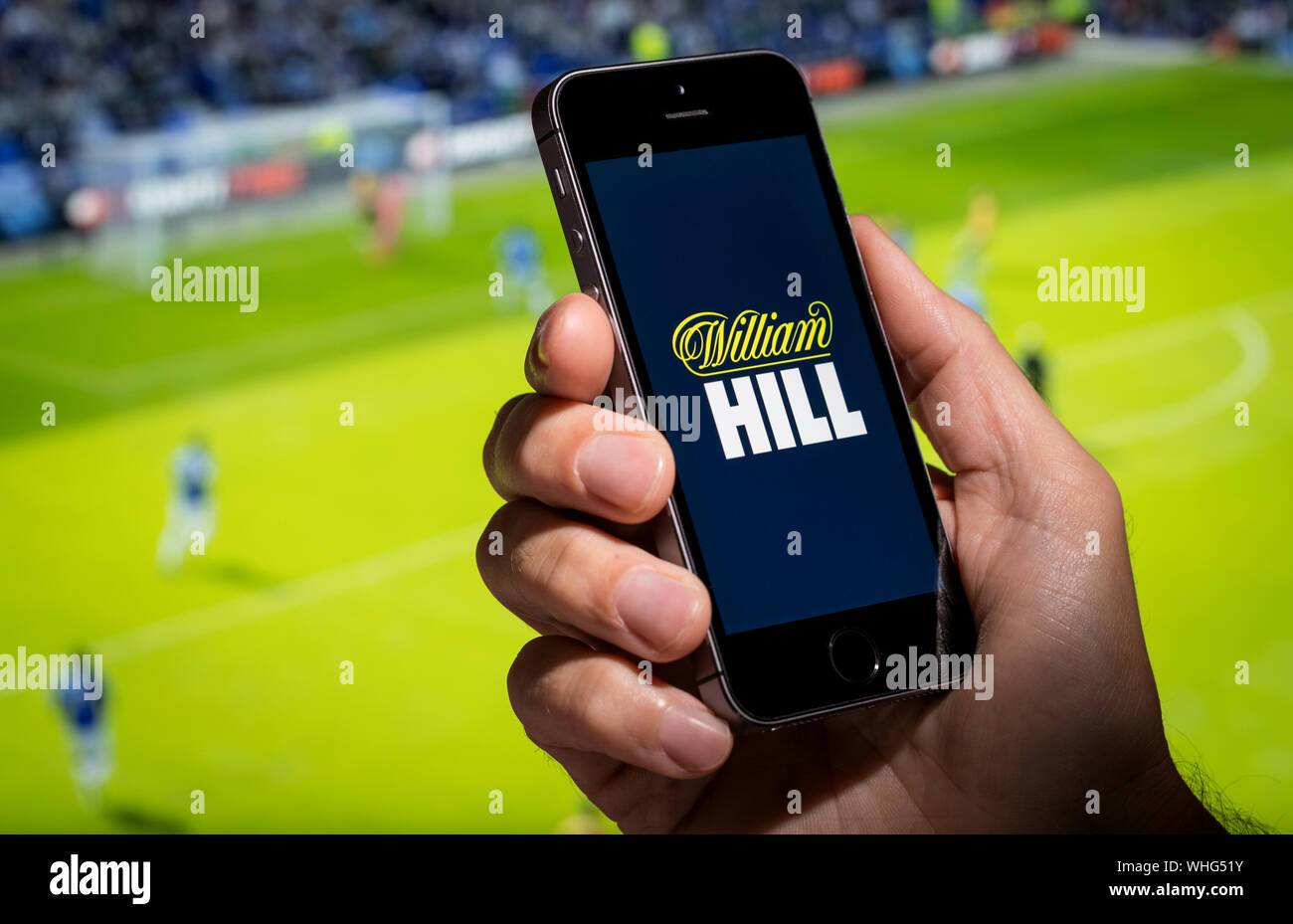 Un homme à la recherche à la William Hill site web app tout en regardant le foot Banque D'Images