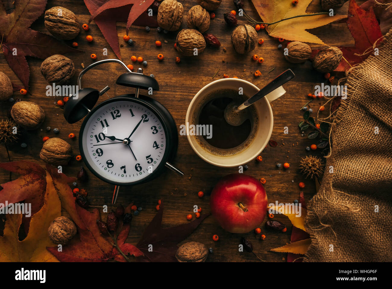 Automne coffee time, vue du dessus télévision laïcs de vintage réveil avec tasse de café chaud sur une table décorée avec des fruits d'automne et de feuilles d'érable sec Banque D'Images