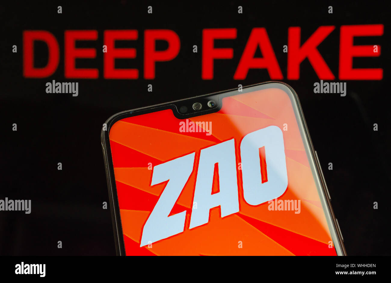 ZAO logo app sur le smartphone et mots rouges des faux sur le fond écran. Zao est en ce moment un numéro un swap face IA app divertissante en Chine. Banque D'Images