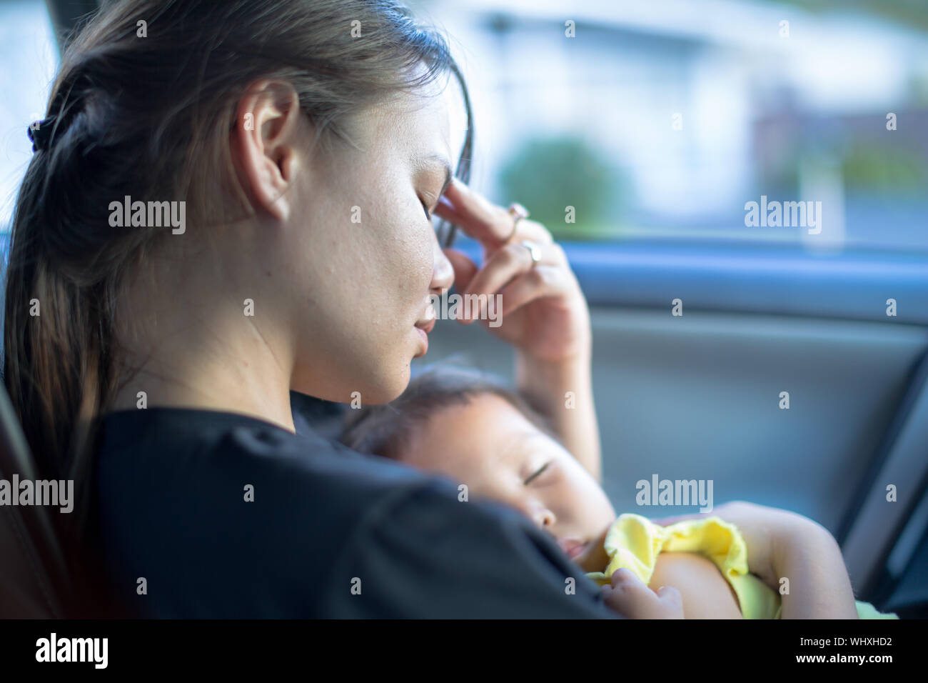 Fatigué a souligné mère tenant dans ses bras alors qu'il attendait dans la voiture Banque D'Images