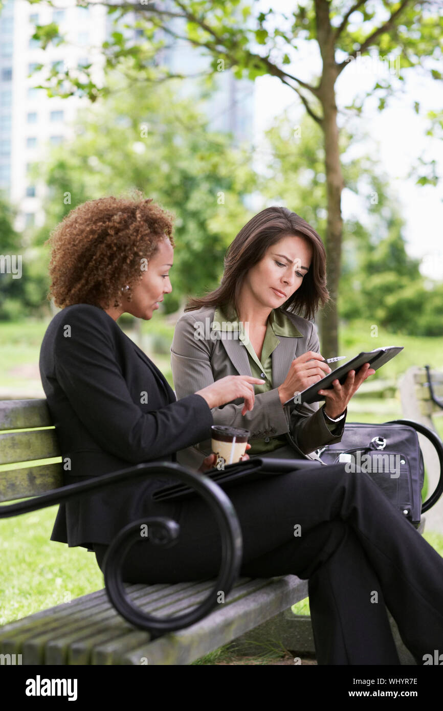 Deux jeunes businesswomen working on park bench Banque D'Images