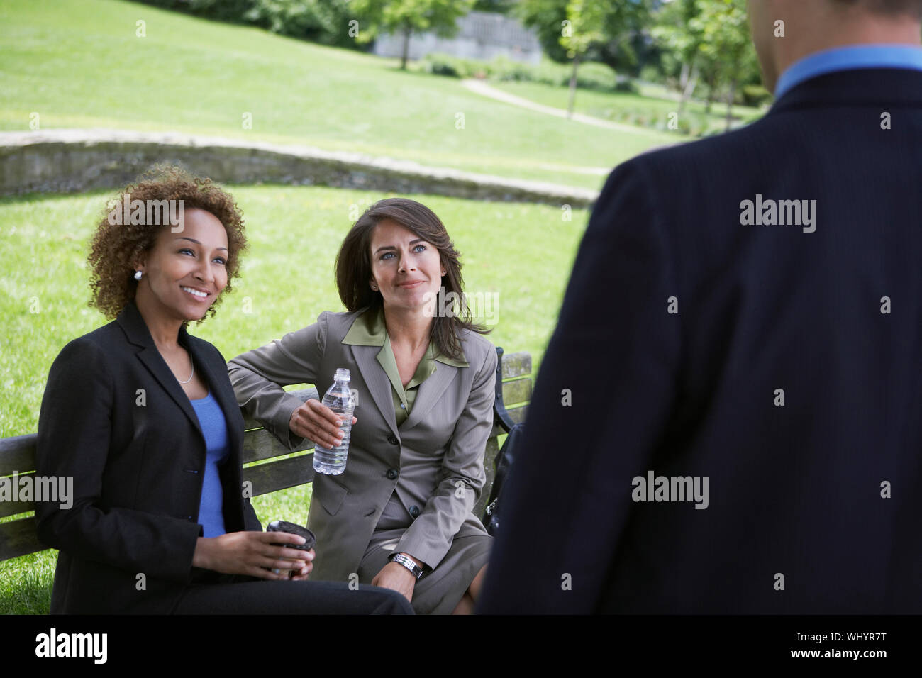 Deux femmes d'multiethnique sur banc de parc à la recherche d'affaires à Banque D'Images
