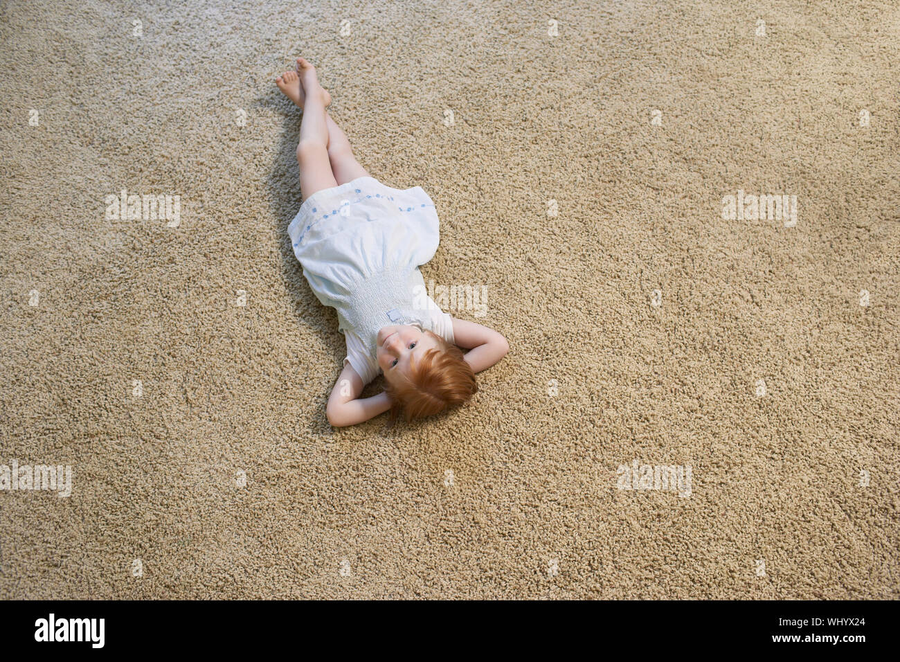 High angle portrait of little girl lying on carpet at home Banque D'Images