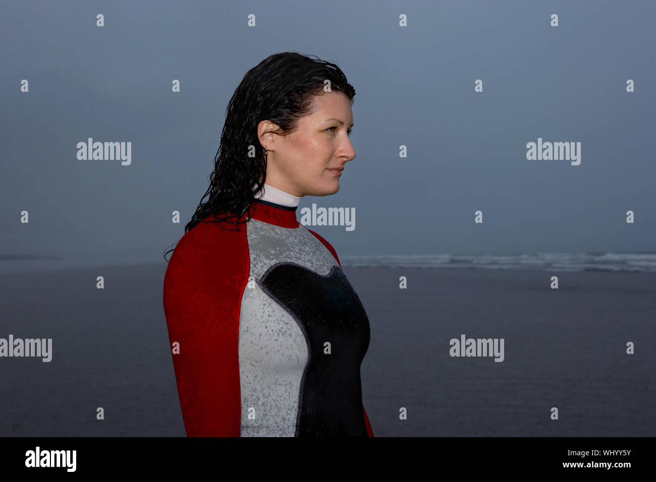 Young woman in wetsuit looking away at beach Banque D'Images