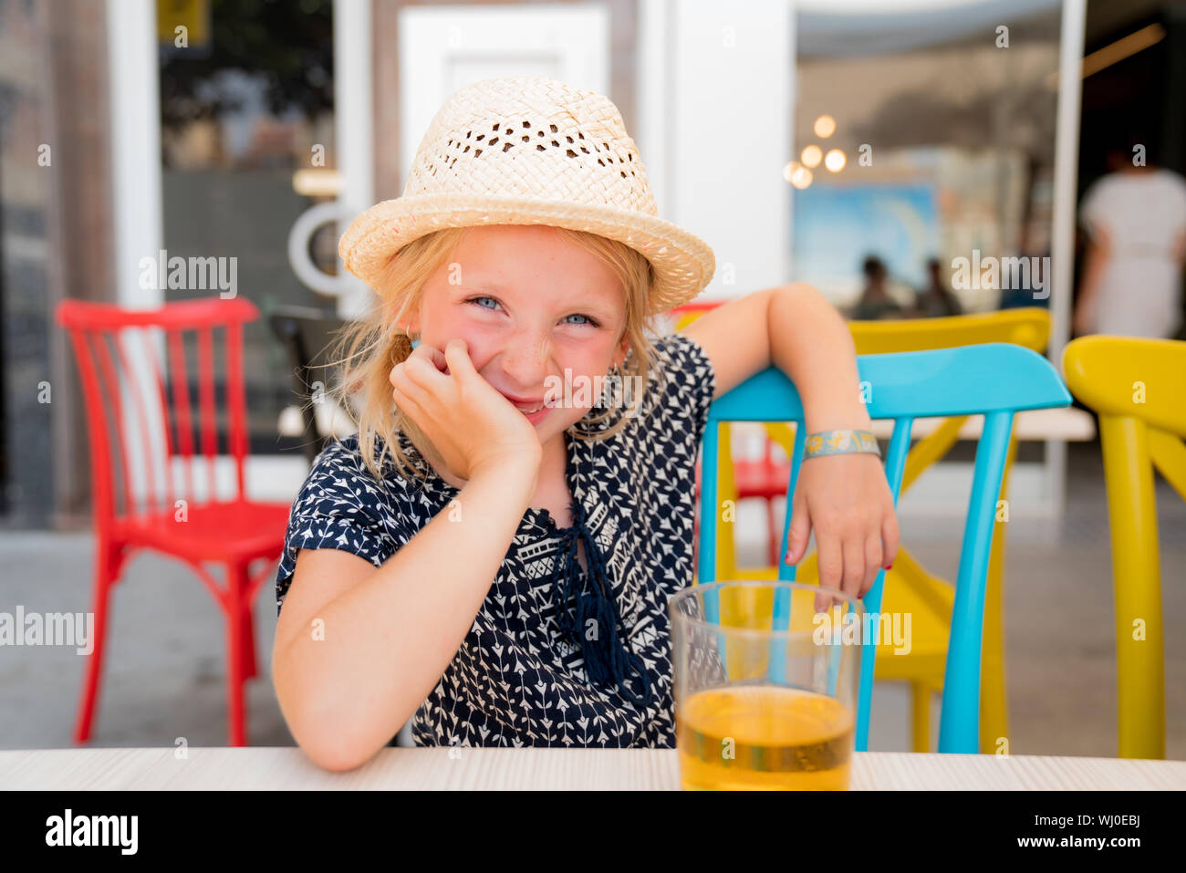 Portrait d'un enfant c'est avoir un bon temps sur une terrasse de café. Boire un verre de soda elle ordonna. girl porte un chapeau pour le soleil Banque D'Images