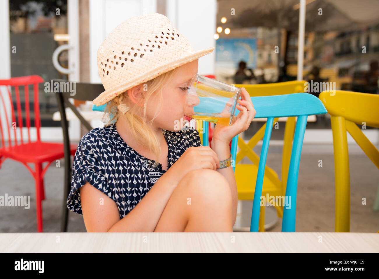 Portrait d'un enfant c'est avoir un bon temps sur une terrasse de café. Boire un verre de soda elle ordonna. girl porte un chapeau pour le soleil Banque D'Images