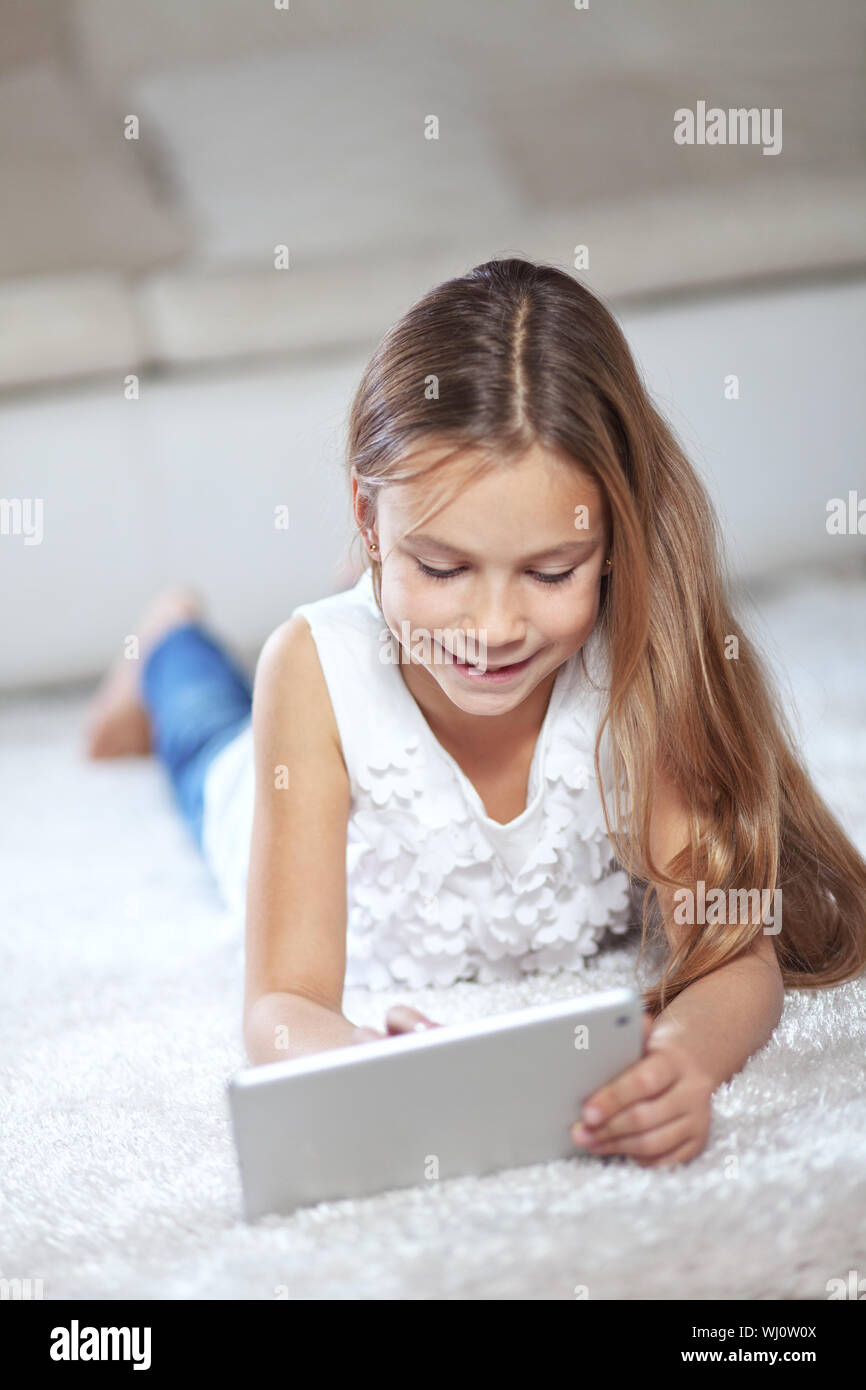 Enfant jouant sur tablet pc assis sur un tapis à la maison Banque D'Images