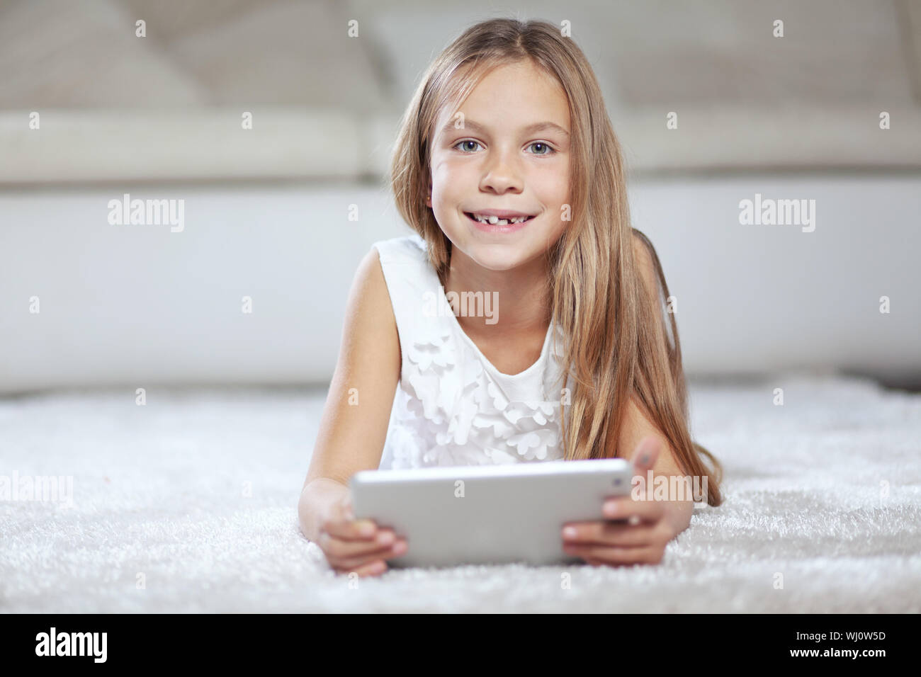 Enfant jouant sur tablet pc assis sur un tapis à la maison Banque D'Images