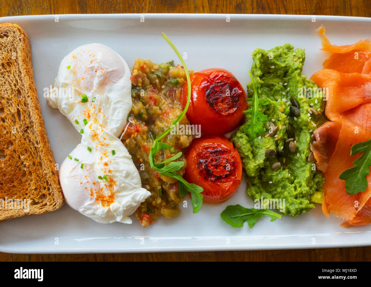 Saumon fumé, deux œufs pochés, Avocat, tomates, une rôtie de blé entier, l'aubergine Banque D'Images