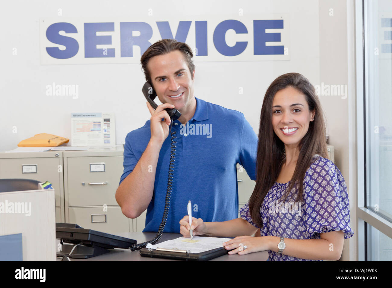 Portrait of man and woman standing in auto repair shop Banque D'Images