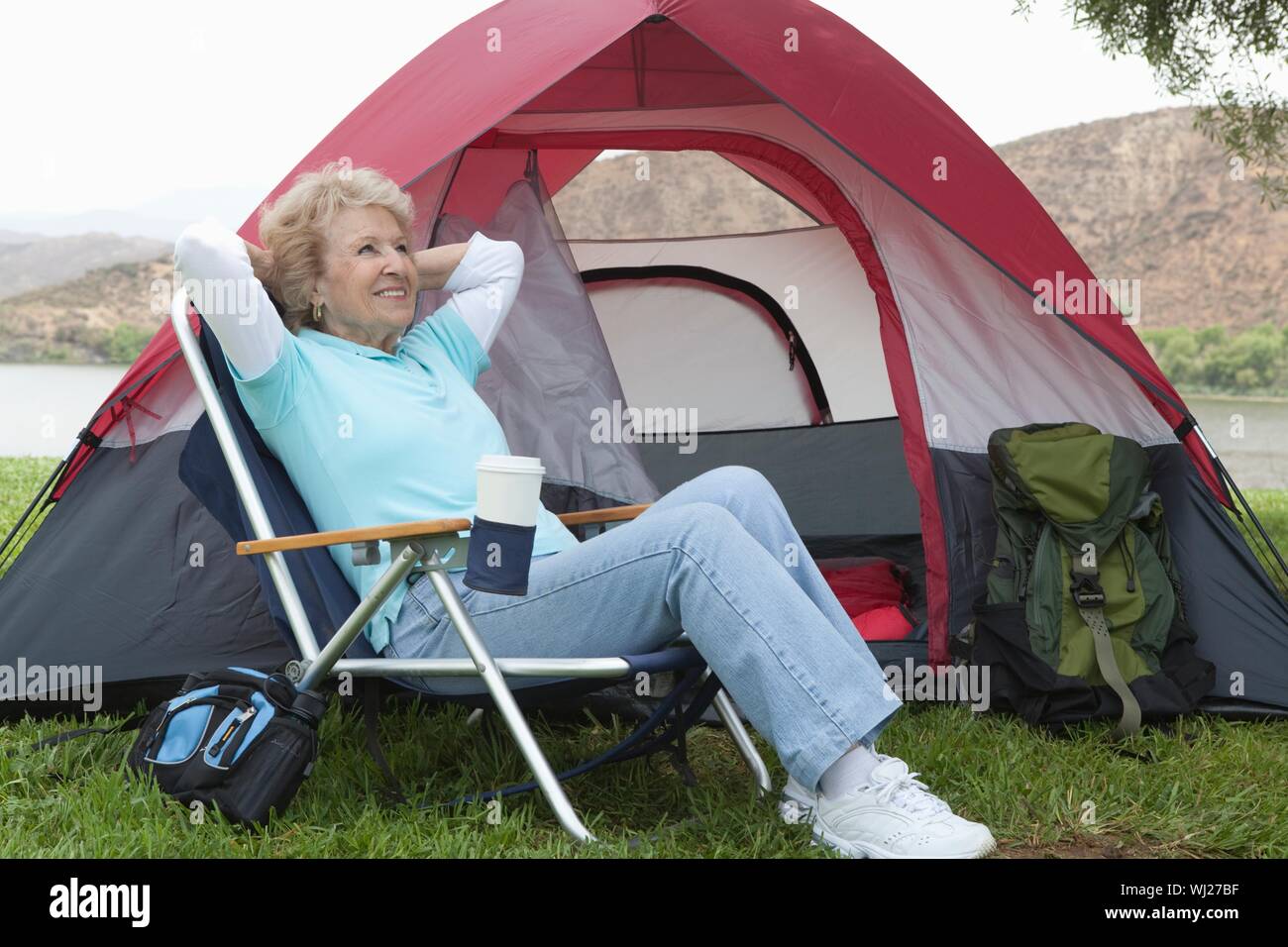 Happy senior woman relaxing on chaise pliante à côté tente de camping Photo  Stock - Alamy