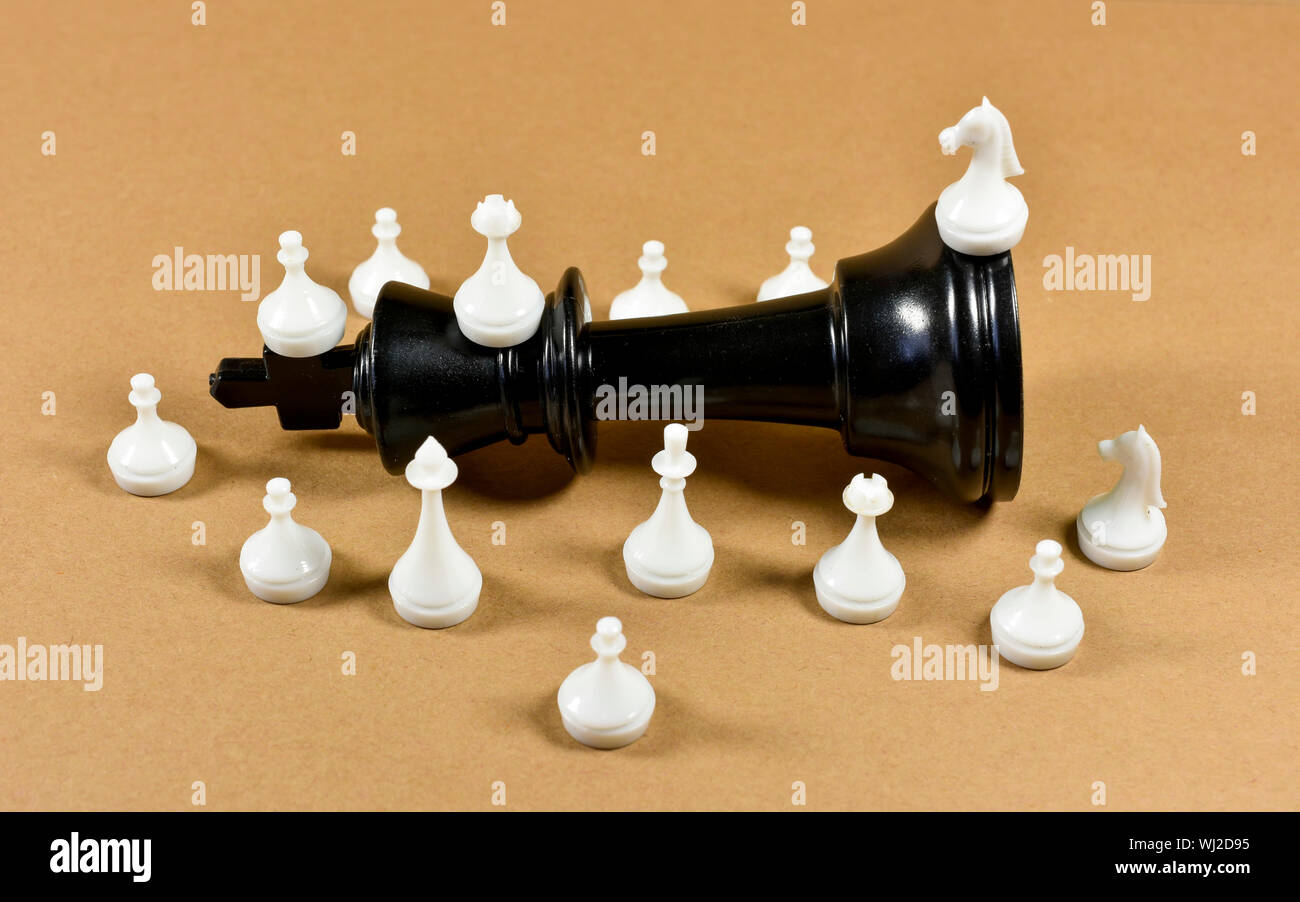 Pièce d'échecs roi noir tombé sur une carte dotée de petites pièces d'échecs blanc qui l'entoure, conceptual image sur le leadership , la concurrence et d'affaires Banque D'Images