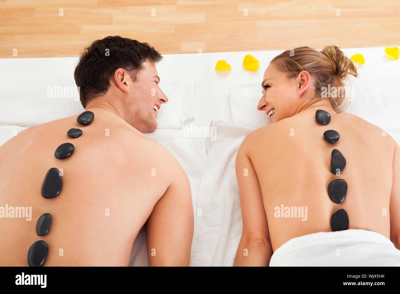 Couple un massage aux pierres chaudes dans un spa où des pierres chauffées sont placées le long de la colonne vertébrale pour détendre les muscles Banque D'Images