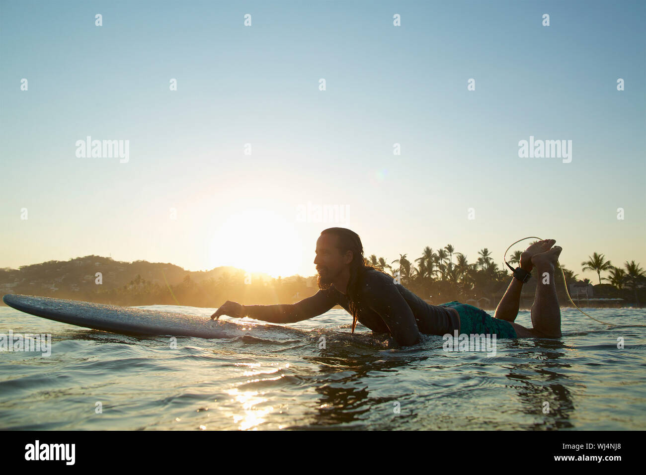 Surfer sur la pagaie mâles coucher soleil océan, Sayulita, Nayarit, Mexique Banque D'Images