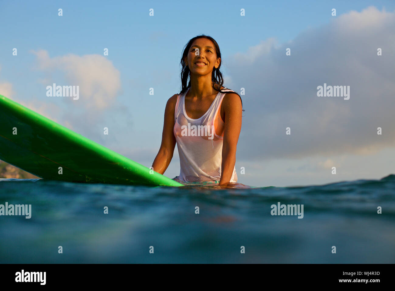 Souriant, confident female surfer en attente sur une planche de surf dans la région de ocean Banque D'Images