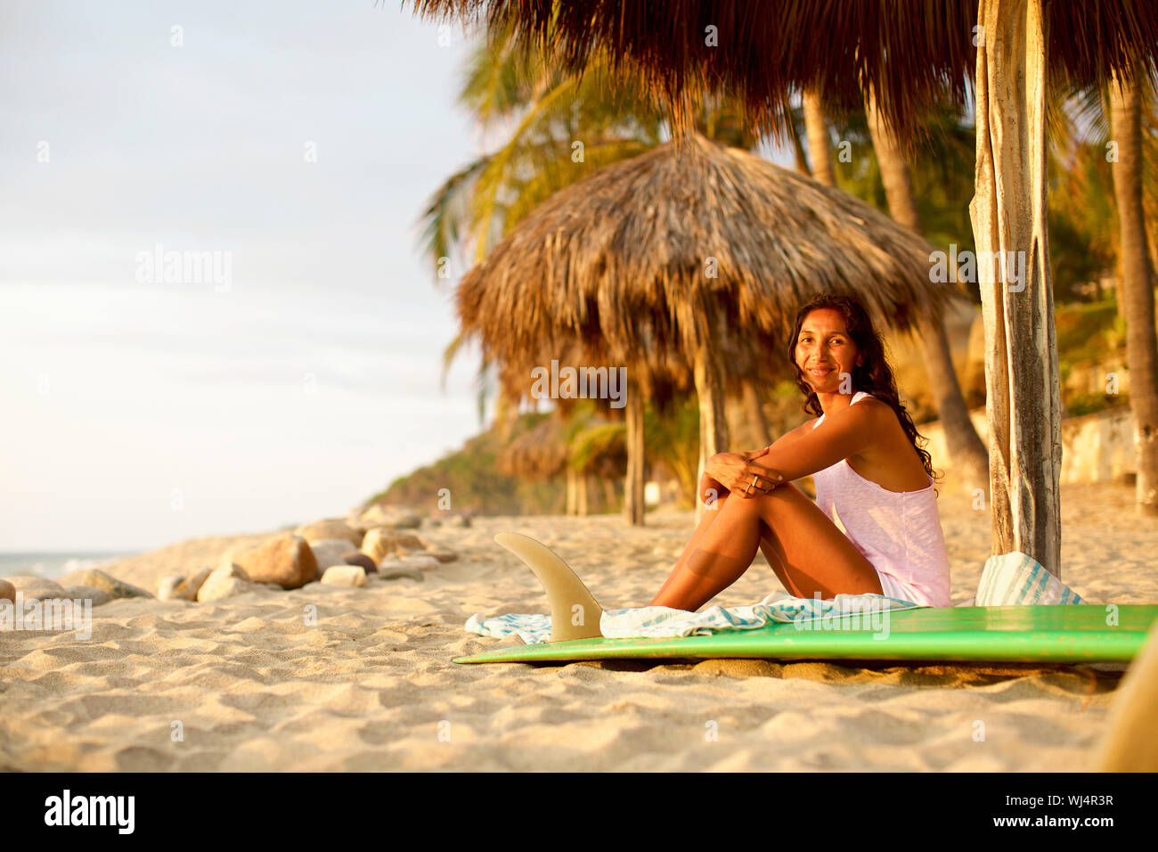 Portrait confident female surfer avec une planche de surf de détente sur la plage ensoleillée, Sayulita, Nayarit, Mexique Banque D'Images